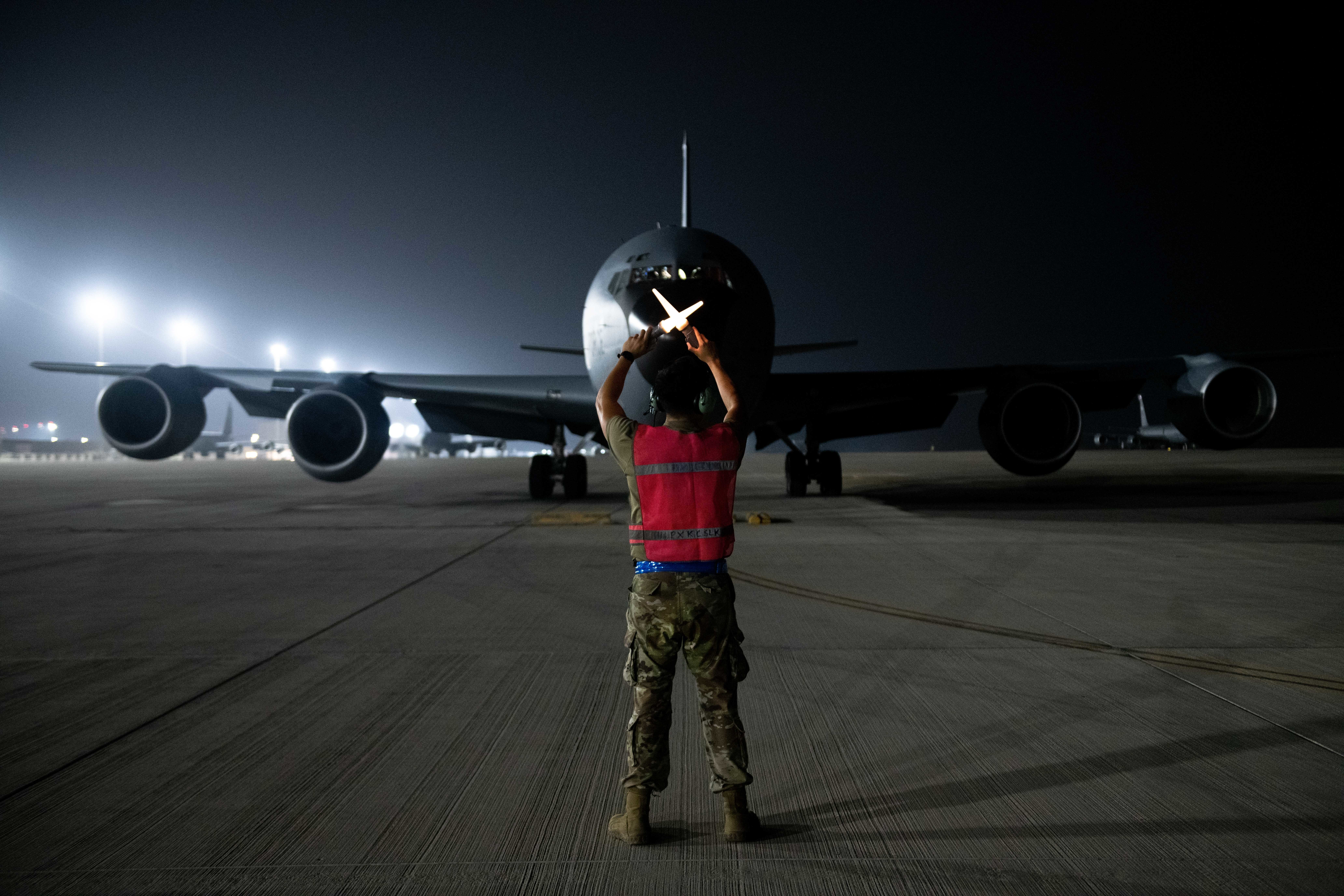 U.S. Air Force Senior Airman Jesse Lookingglass, a maintainer with the 379th Expeditionary Aircraft Maintenance Squadron, guides a KC-135 into a parking spot on Al Udeid Air Base, Qatar, Aug. 1, 2022. After landing, the aircraft taxis to the ramp, where any required maintenance is performed. (U.S. Air National Guard photo by Airman 1st Class Constantine Bambakidis)