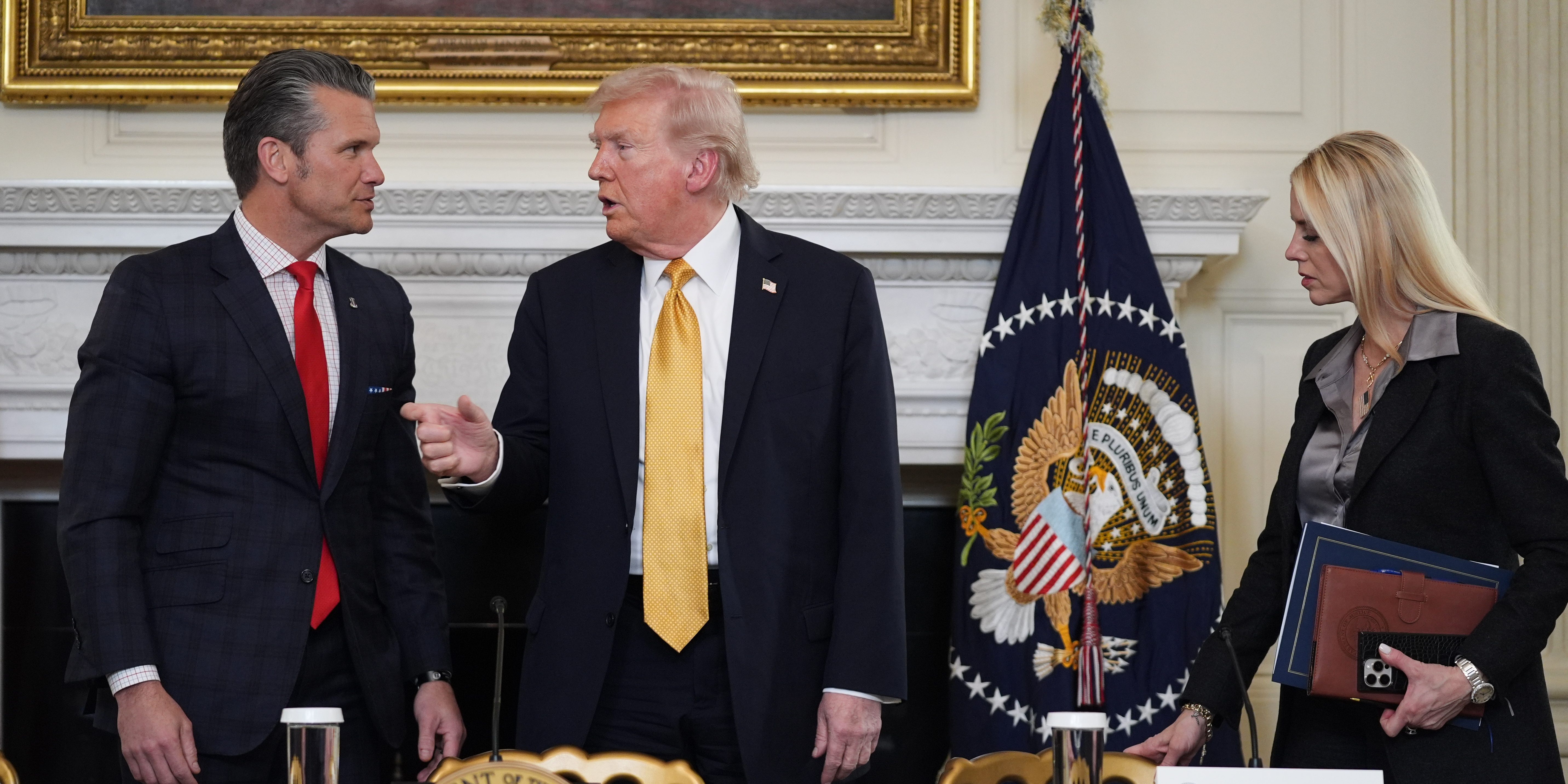 President Donald Trump talks with Defense Secretary Pete Hegseth after a roundtable on cartels in the State Dining Room of the White House, Thursday, Oct. 23, 2025, in Washington, as Attorney General Pam Bondi watches.