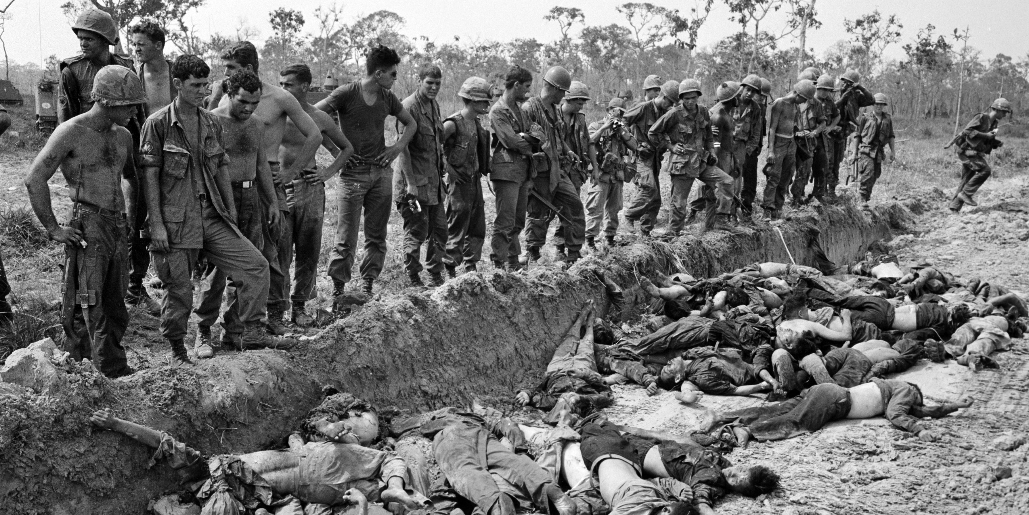 U.S. soldiers of the 3rd Brigade, 4th Infantry Division, look on a mass grave after a day-long battle against the Viet Cong 272nd Regiment, about 60 miles northwest of Saigon, in March 1967.