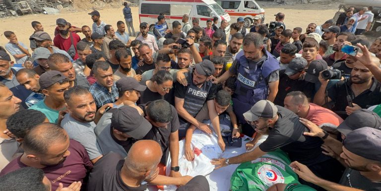 Men gather around the body of slain photojournalist Anas Al-Sharif at his funeral on August 11, 2025 following an Israeli attack on the press tent in Gaza City.