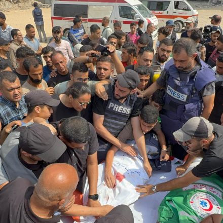 Men gather around the body of slain photojournalist Anas Al-Sharif at his funeral on August 11, 2025 following an Israeli attack on the press tent in Gaza City.