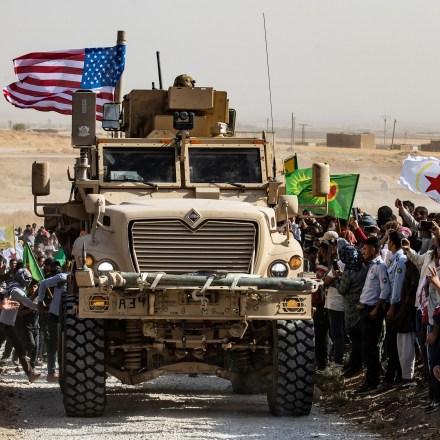 Syrian Kurds gather around a US armoured vehicle during a demonstration against Turkish threats next to a US-led international coalition base on the outskirts of Ras al-Ain town in Syria's Hasakeh province near the Turkish border on October 6, 2019. - Ankara had reiterated on October 5 an oft-repeated threat to launch an "air and ground" operation in Syria against a Kurdish militia it deems a terrorist group. (Photo by Delil SOULEIMAN / AFP) (Photo by DELIL SOULEIMAN/AFP via Getty Images)
