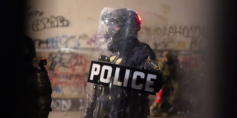 PORTLAND, OR - JULY 24: A federal officer stands guard inside the perimeter fence of the Mark O. Hatfield U.S. Courthouse on Thursday, July 24, 2020 in Portland, Oregon.  Protesters continued to clash with federal officers Friday morning as President Trump announced plans to deploy similar federal forces to other U.S. cities. (Photo by Nathan Howard/Getty Images)