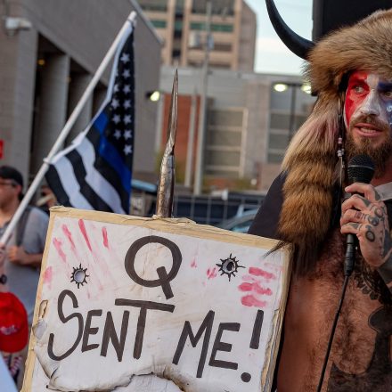 Jake Angeli, known as the "QAnon Shaman,"  holds a sign reading "Q Sent Me" as supporters of US President Donald Trump gather to protest outside the Maricopa County Election Department as counting continues after the US presidential election in Phoenix, Arizona, on November 5, 2020. President Donald Trump erupted on November 5 in a tirade of unsubstantiated claims that he has been cheated out of winning the US election as vote counting across battleground states showed Democrat Joe Biden steadily closing in on victory. (Photo by OLIVIER  TOURON / AFP) (Photo by OLIVIER  TOURON/AFP via Getty Images)