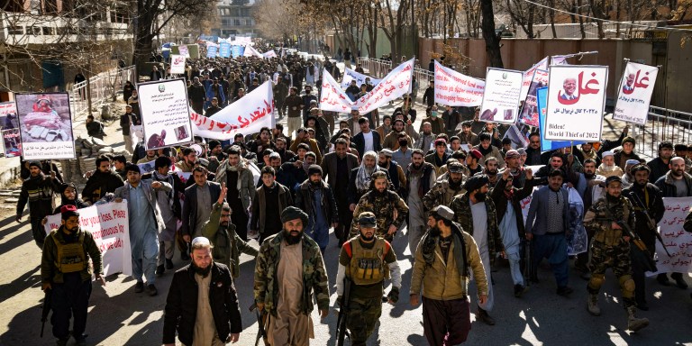 People hold placards as they march during a protest against the recent remarks by U.S. President Joe Biden to freeze Afghanistan's assets, in Kabul on February 15, 2022. (Photo by Sahel ARMAN / AFP) (Photo by SAHEL ARMAN/AFP via Getty Images)