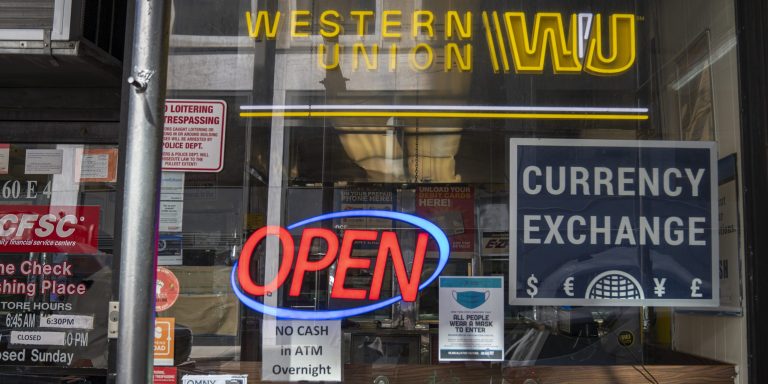 A shop window displays signs for a currency exchange, Western Union and check cashing services March 21, 2022 in New York City.