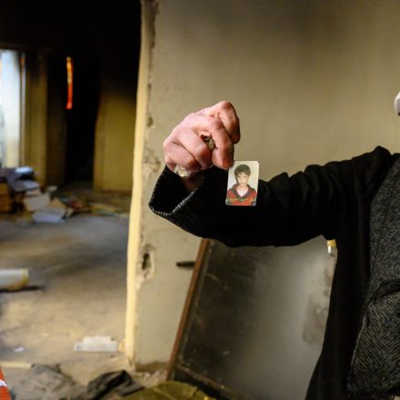 A Syrian woman called Um Imad holds up a passport photo at Syria's Palestine Branch prison in Damascus, where her daughter was held for months, on December 17, 2024.