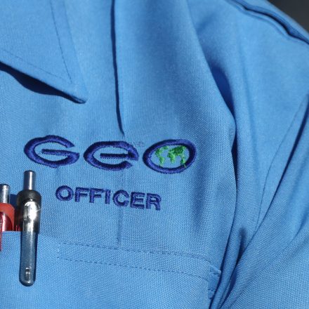 An officer wears the logo of the GEO Group private prison company outside the Adelanto ICE Processing Center detention facility in Adelanto, California, on July 11, 2025.