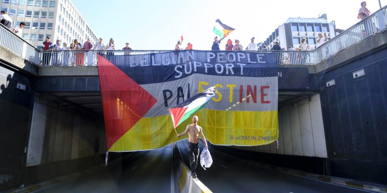 BRUSSELS, BELGIUM - SEPTEMBER 7: People hang a giant Palestine flag on a tunnel while a shirtless man is walking in balance on the central pillar of the urban highway in the street of Brussels for Gaza on September 7, 2025 in Brussels, Belgium. The second edition of the "Red Line for Gaza" protest began today at the Gare du Nord in Brussels. More than 200 organizations, associations, and trade unions gathered to condemn Israel's policies in the Gaza war, as well as companies and countries deemed complicit in "crimes committed by the Israeli government." (Photo by Thierry Monasse/Getty Images)