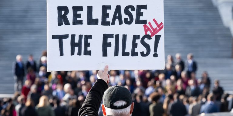 TOPSHOT - A protester holds a sign related to the release of the Jeffrey Epstein case files outside the US Capitol in Washington, DC, November 12, 2025. Democrats released emails Wednesday in which Jeffrey Epstein suggested Donald Trump was aware of the disgraced financier's sexual abuse and had "spent hours" with one of his victims at his house. Trump has denied any knowledge of the sex-trafficking activities of his former friend, who died by suicide in 2019 as he was in prison awaiting trial, and the White House accused Democrats of pushing a "fake narrative" by sharing the mails. (Photo by SAUL LOEB / AFP) (Photo by SAUL LOEB/AFP via Getty Images)