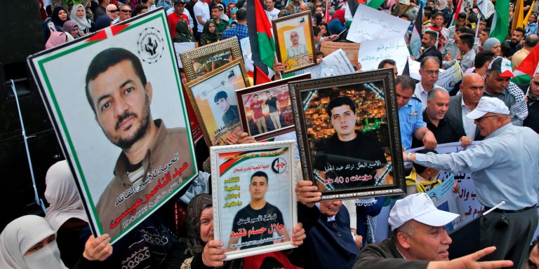 Palestinians hold portraits of relatives jailed in Israeli prisons as they protest to demand for their release during a demonstration to mark the Prisoners' Day in the northern West Bank city of Nablus on April 17, 2018. / AFP PHOTO / JAAFAR ASHTIYEH        (Photo credit should read JAAFAR ASHTIYEH/AFP/Getty Images)